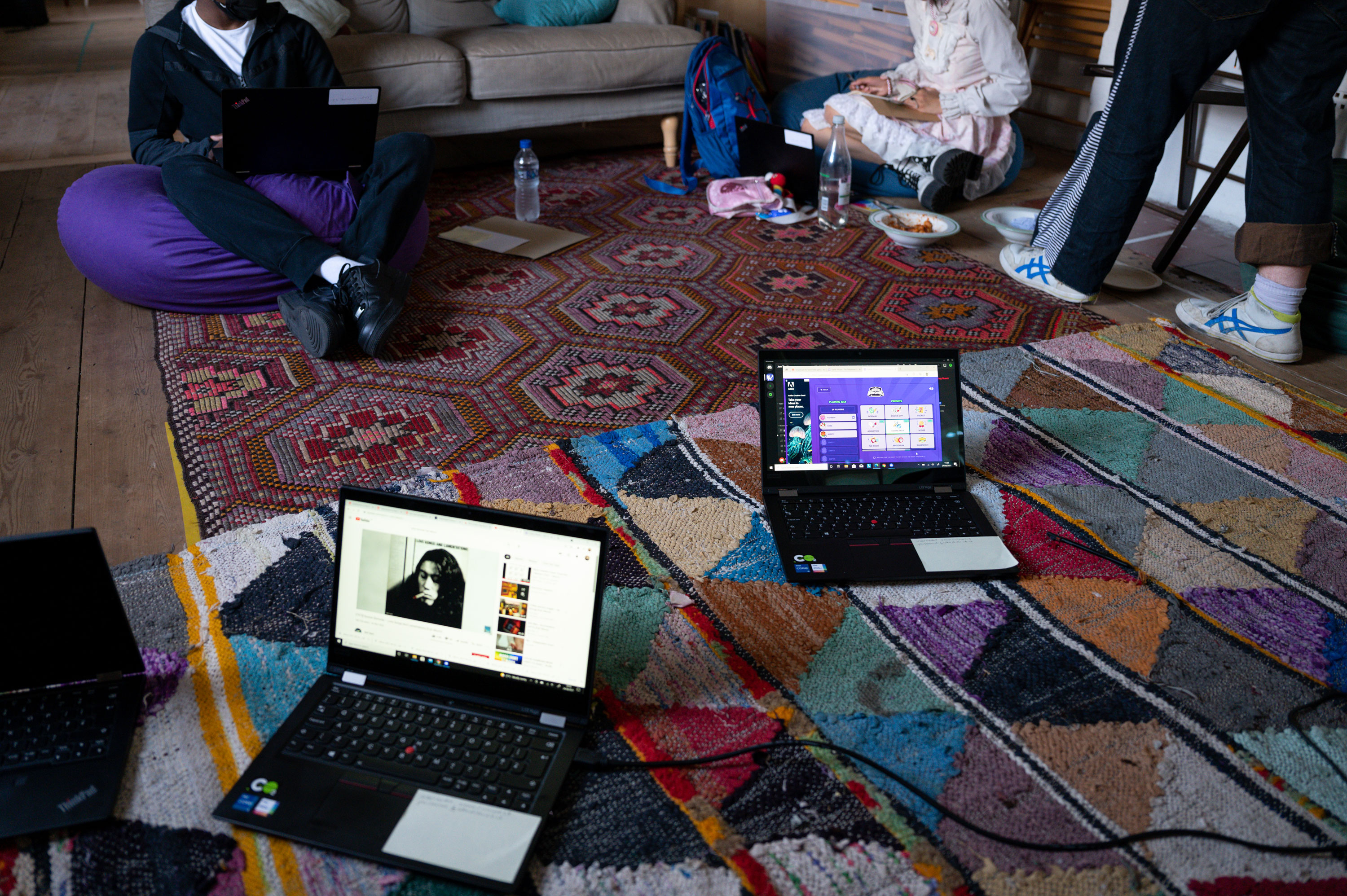 Two participants sitting on the floor using laptops to create digital art work