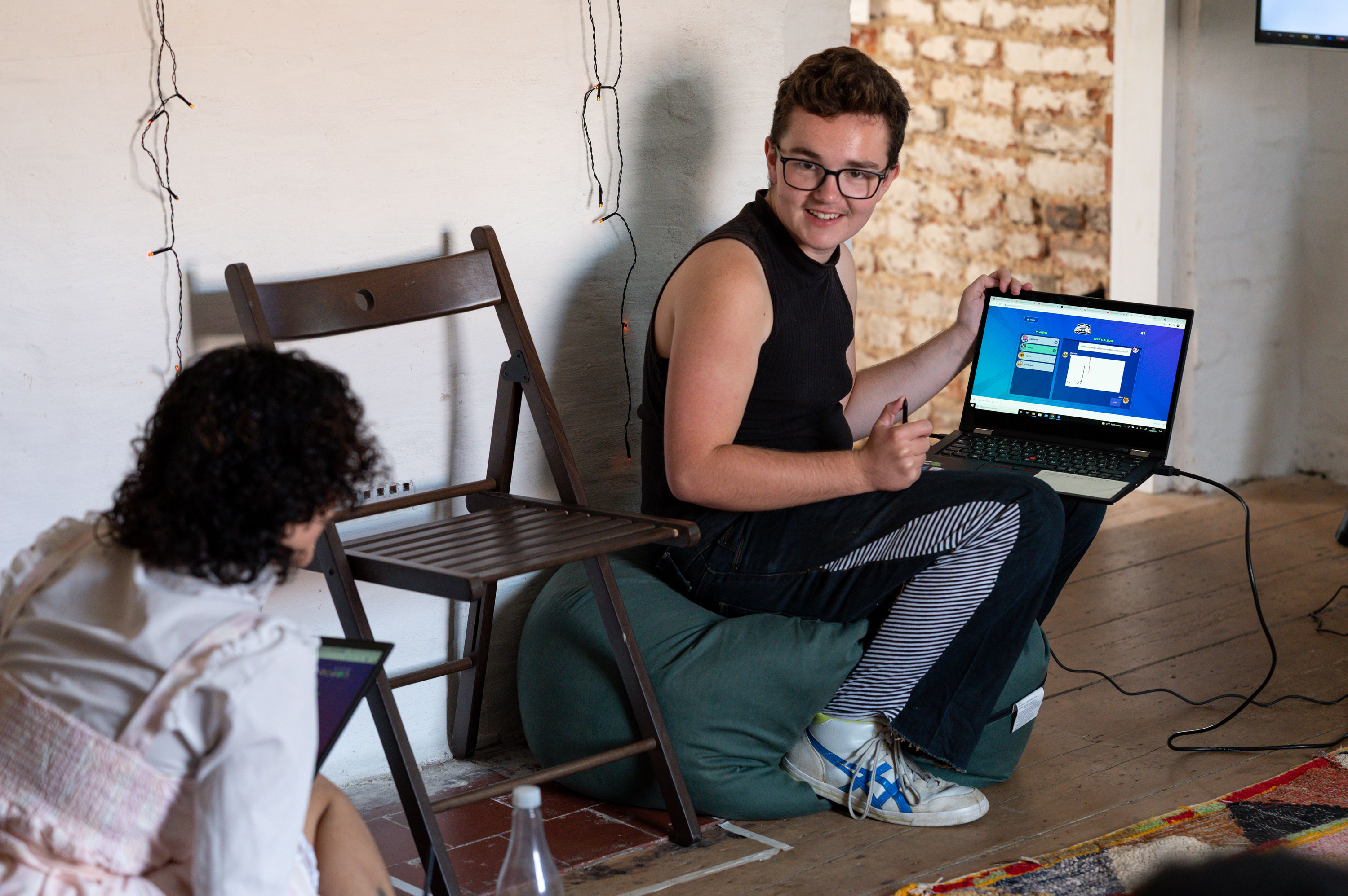 A white person, short haired person using a laptop to present to a young person