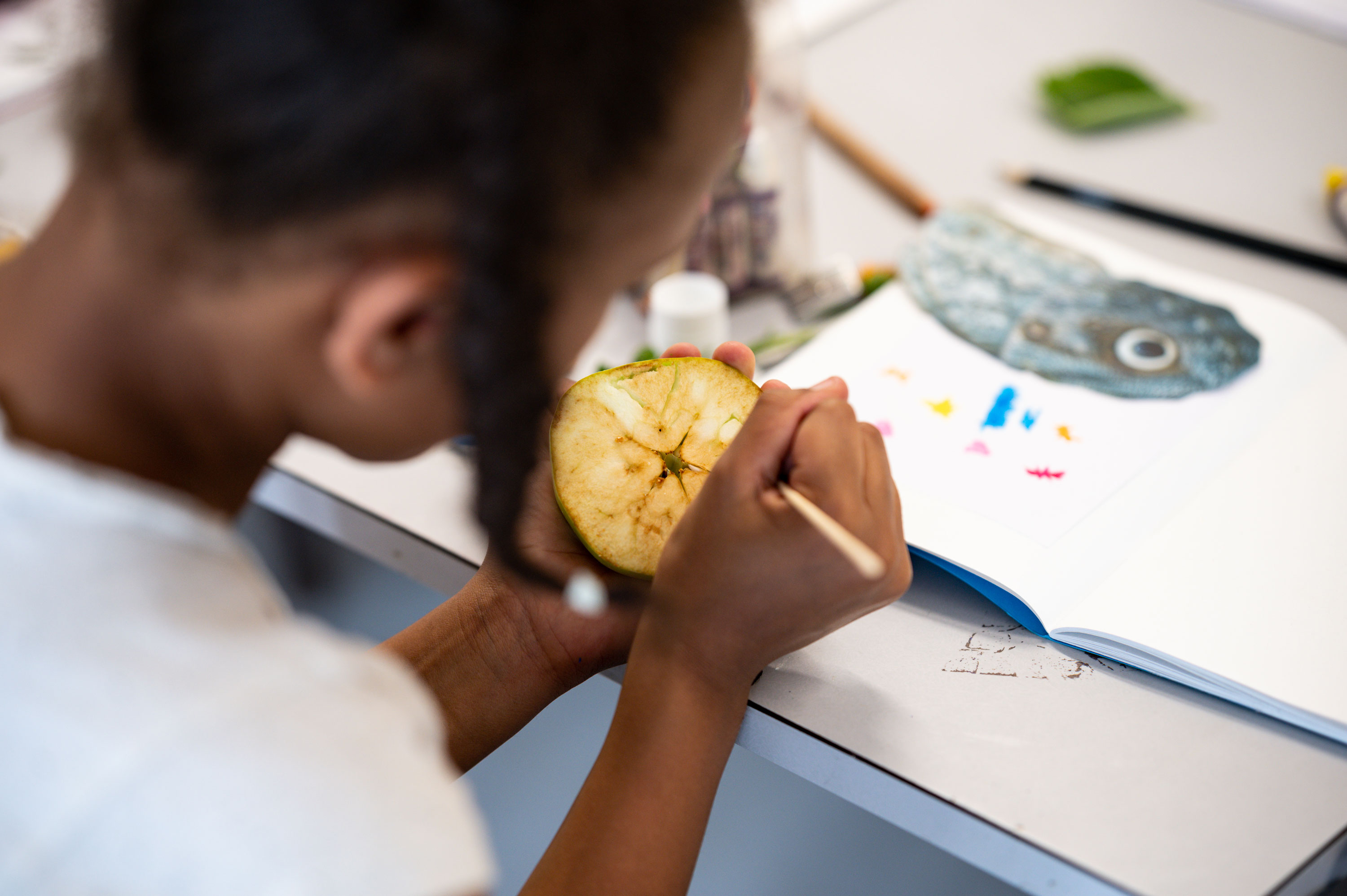 A young person using a cutting knife to create a pattern in a fruit